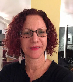 Headshot of Deborah Batterman. She has short curly red hair and wears glasses.