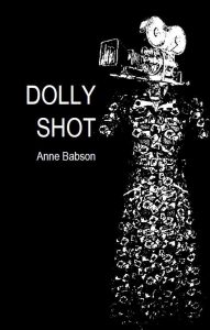 The cover of Dolly Shot has a black background and an abstract dress with a video camera instead of a head above the dress.