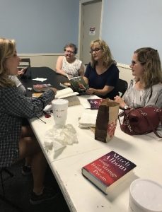 Four women sit at a long table having a discussion.