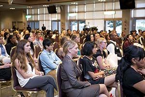 Room filled with people, mostly women, sitting in chairs.