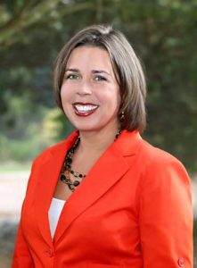 Photo of Nicole Ayers, former editor of The Bookwoman, standing outside and smiling.